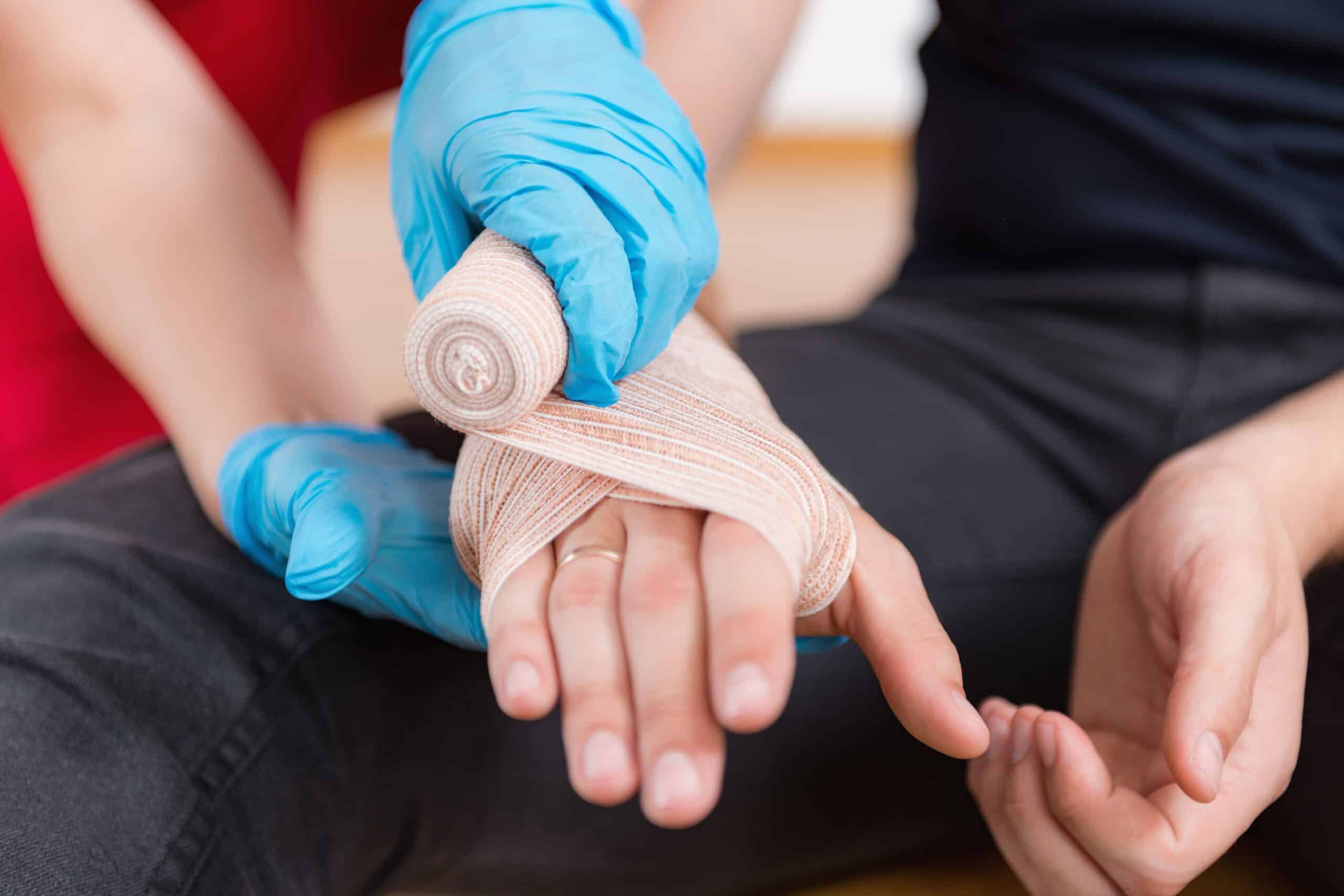 Link Resources first aid and CPR training worker applying bandage to injured hand