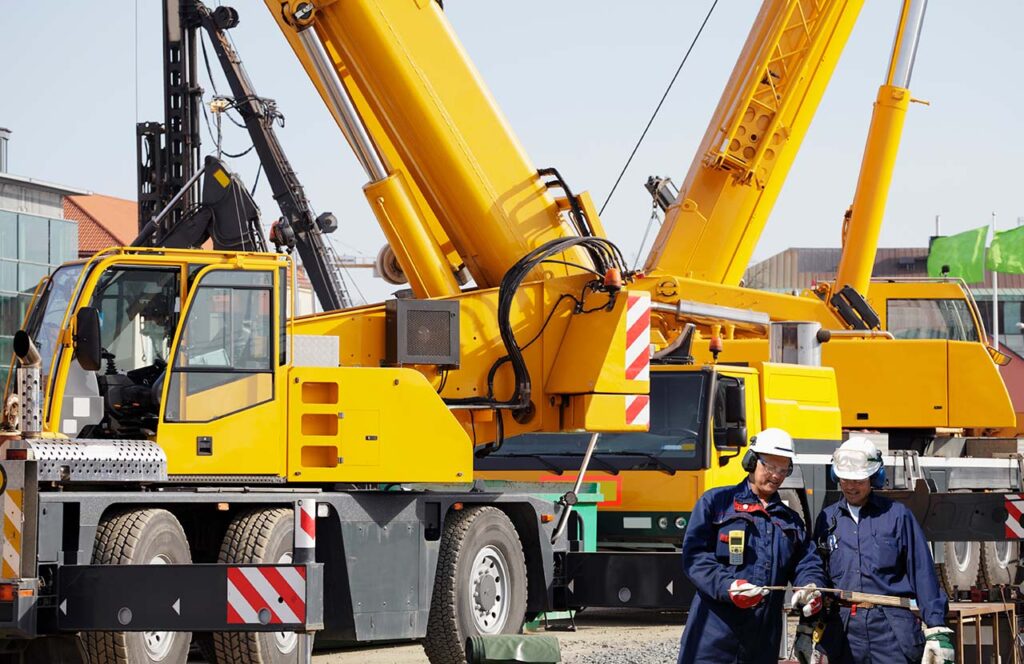 A large mobile crane with outriggers extended is positioned on a construction site.