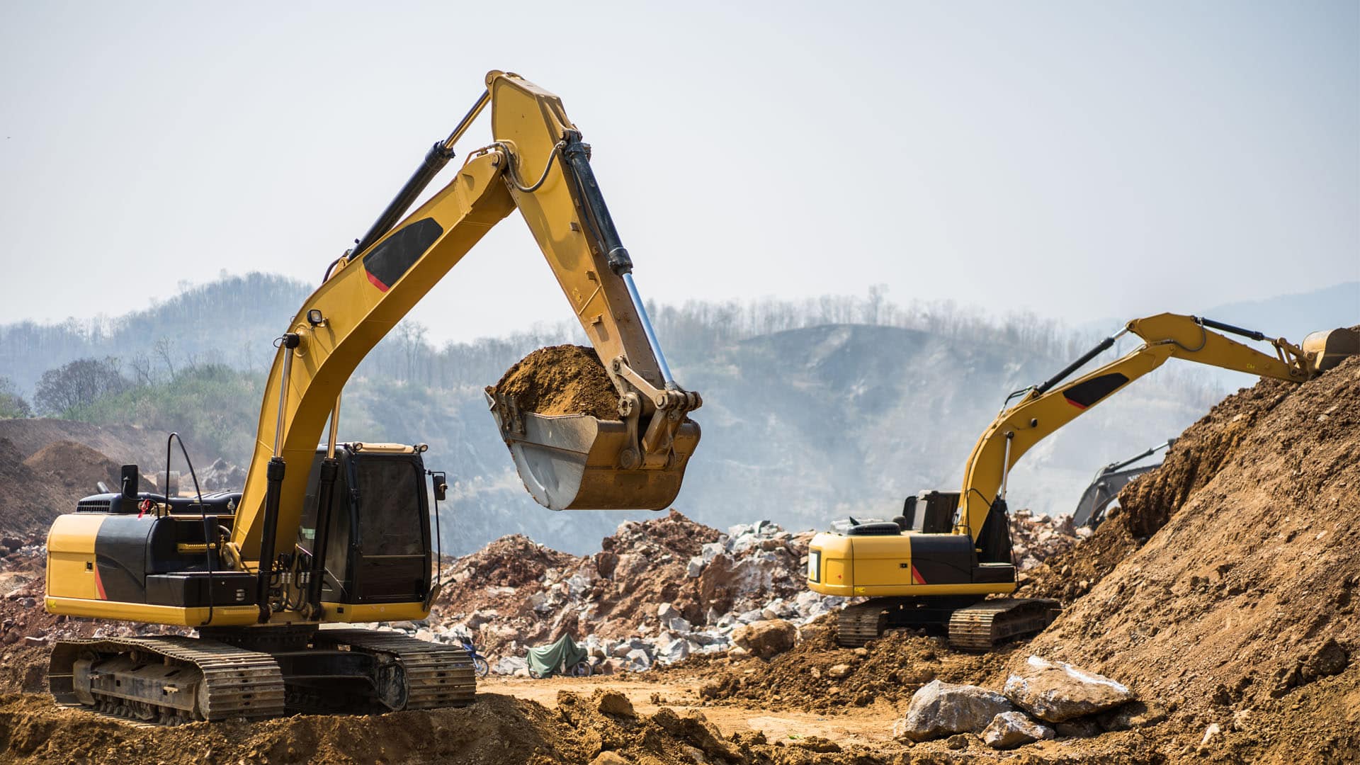 Two yellow excavators working on a construction site.